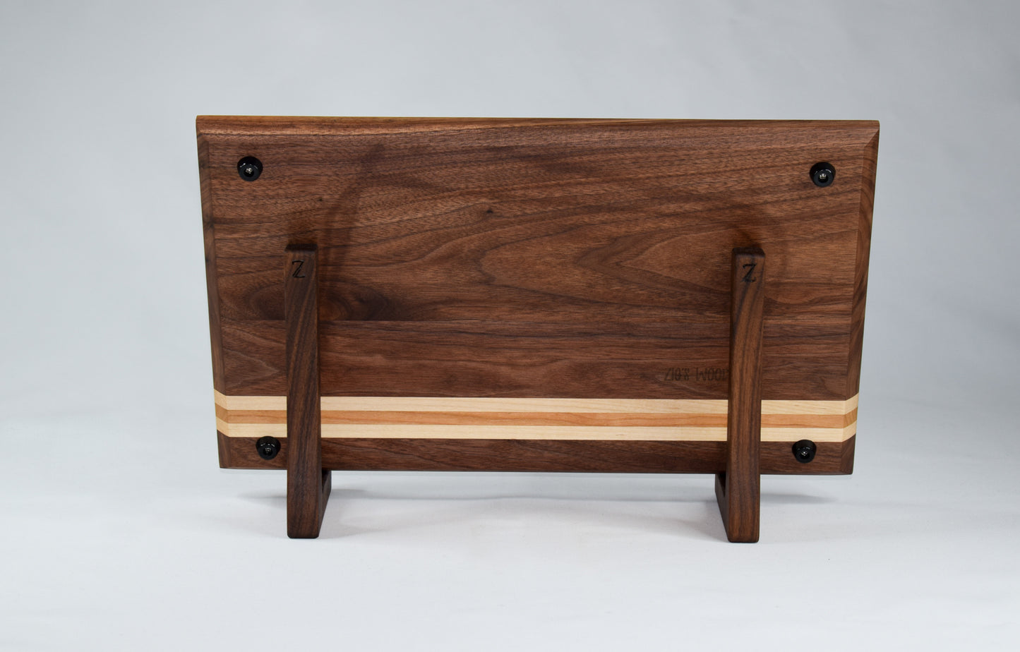 This striped cutting board is the perfect addition to any kitchen with its simple alternating stripes of maple and cherry hardwoods against a walnut backdrop. Complete with non-skid rubber feet for a sturdy cutting surface, this cutting board will not only provide functionality for the chef in your home, but will also serve as a statement piece in the kitchen.