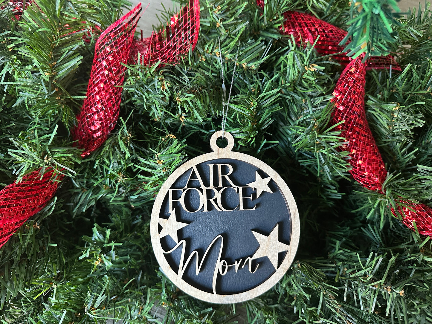 Handmade wood Christmas ornament. Black ornament with light colored birchwood words on top. Words read "Air Force Mom."