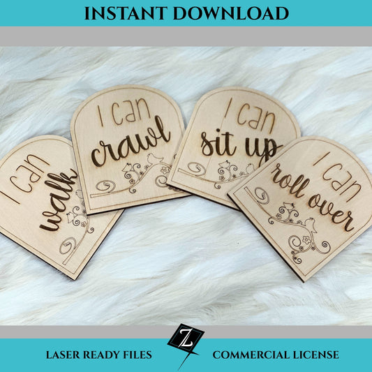 Laser-engraved wooden milestone signs reading “I can walk,” “I can crawl,” “I can sit up,” and “I can roll over,” each with floral and bird designs on arched wood pieces, displayed on soft faux fur.