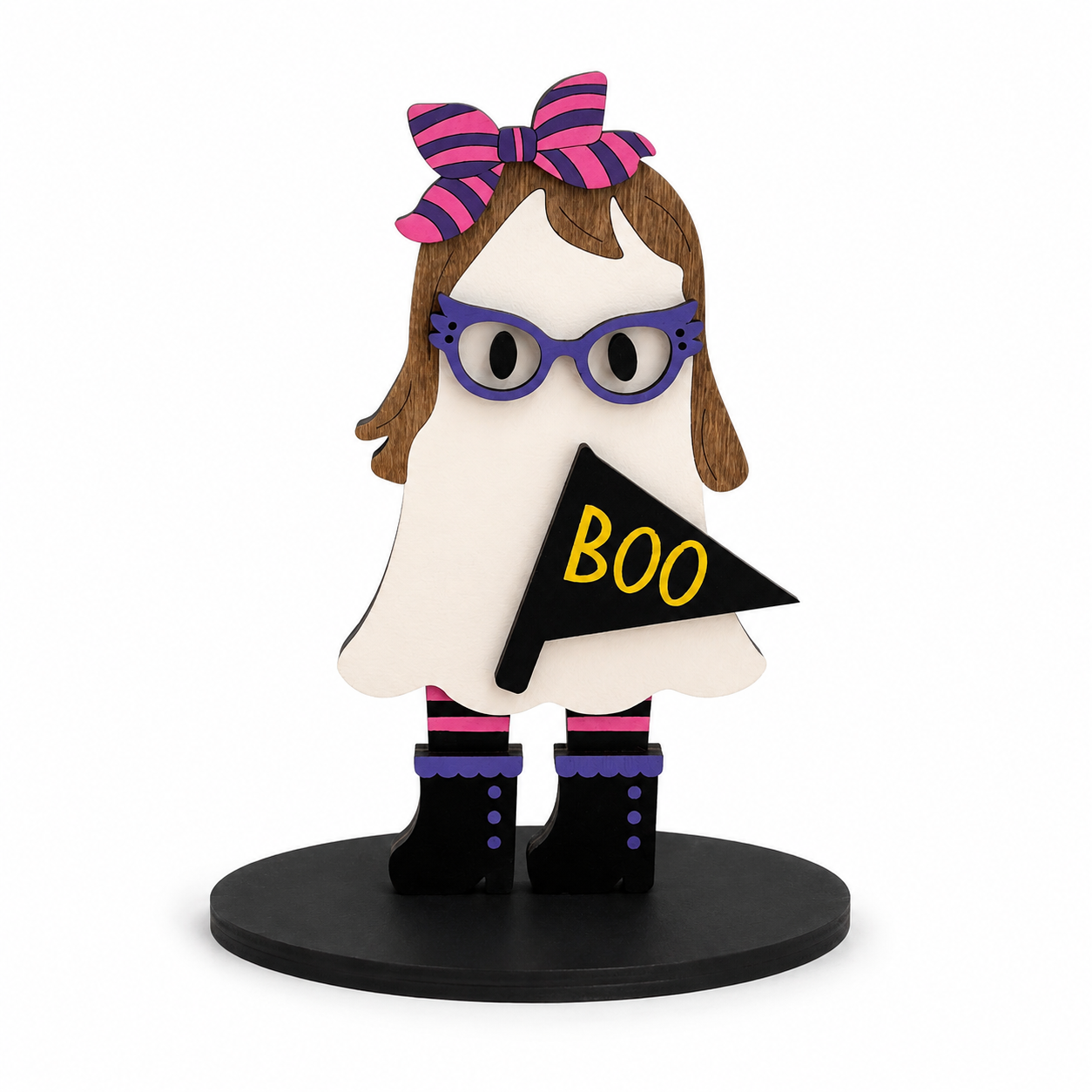 A ghost-shaped decorative figure with brown hair, a pink and purple striped bow, purple glasses, black boots, and a black pennant that says BOO in yellow, standing on a round black base against a white background.