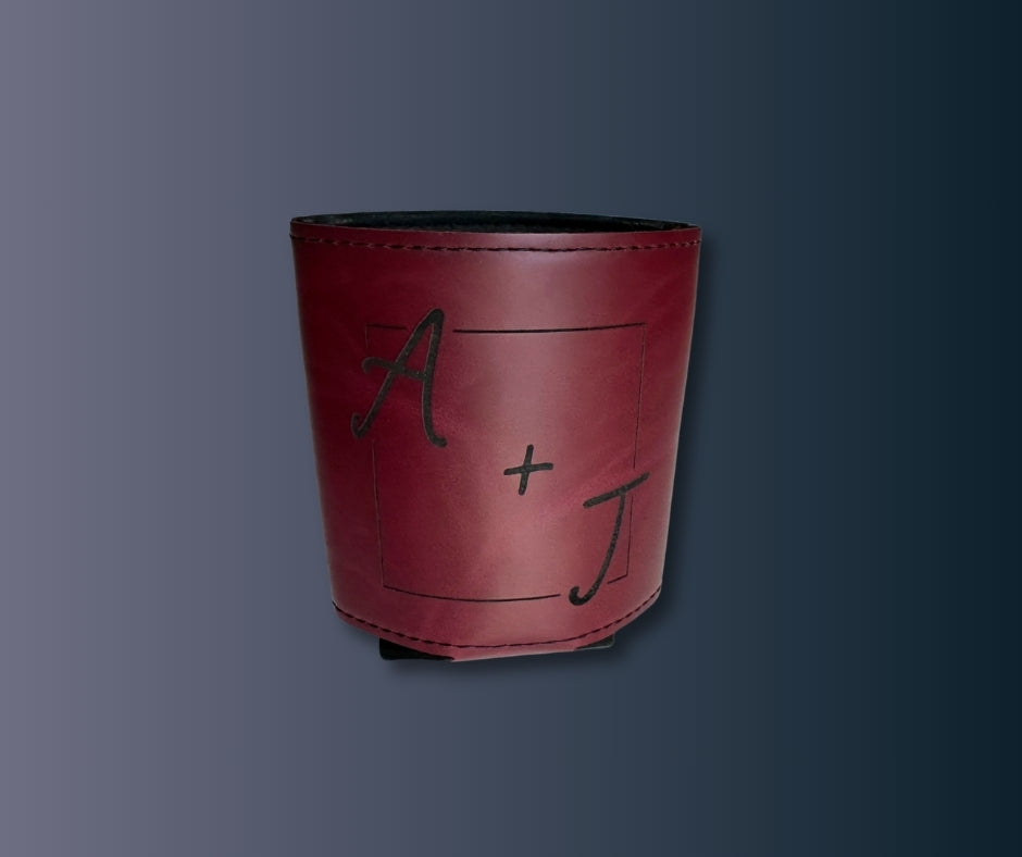 Personalized leatherette koozie in maroon with engraved initials A + J, stitched edges, displayed on dark background.