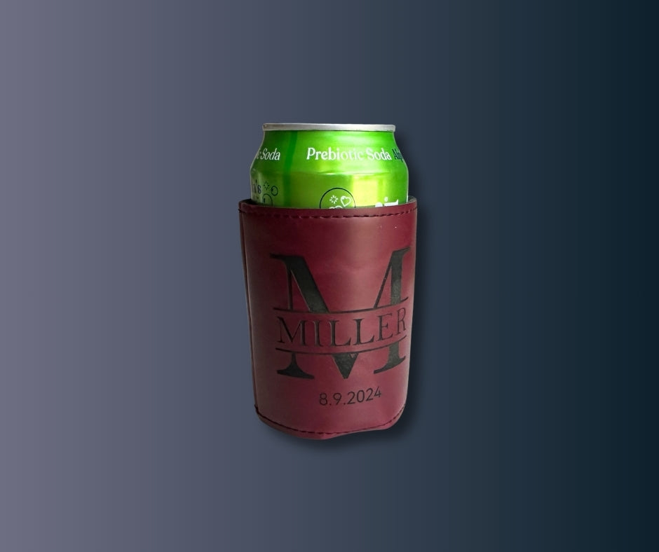 Custom maroon leatherette koozie engraved with large letter M, family name Miller, and date 8.9.2024, shown against dark background.