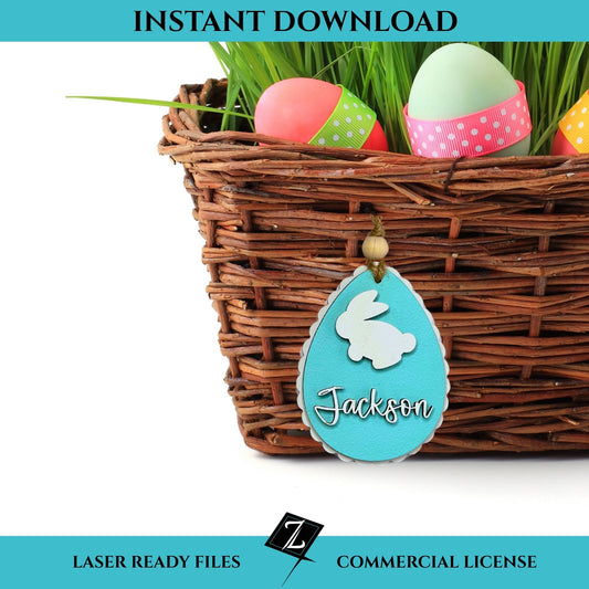 Wicker Easter basket filled with colorful eggs and grass, featuring a hanging personalized basket tag shaped like a scalloped egg. The tag is turquoise with a white bunny silhouette and “Jackson” in layered cursive script. Banner reads “Instant Download - Laser Ready Files - Commercial License” with ZW Digital logo.