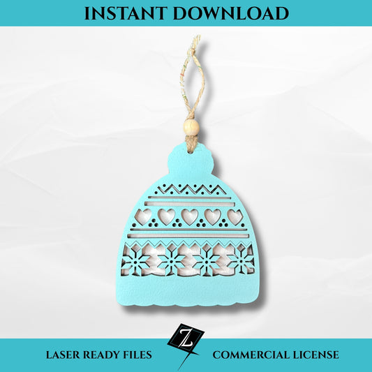 Layered laser-cut ornament shaped like a winter hat with hearts, zigzags, and snowflake cutout details, painted light blue and topped with a wooden bead and string hanger.