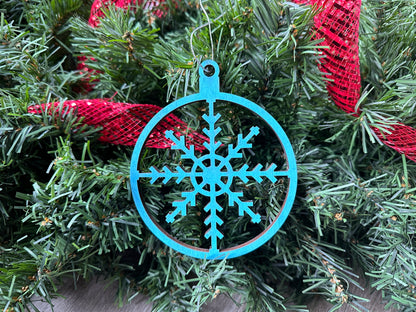 An intricate, blue-colored, laser cut snowflake ornament, locally made in Georgia with Birchwood.