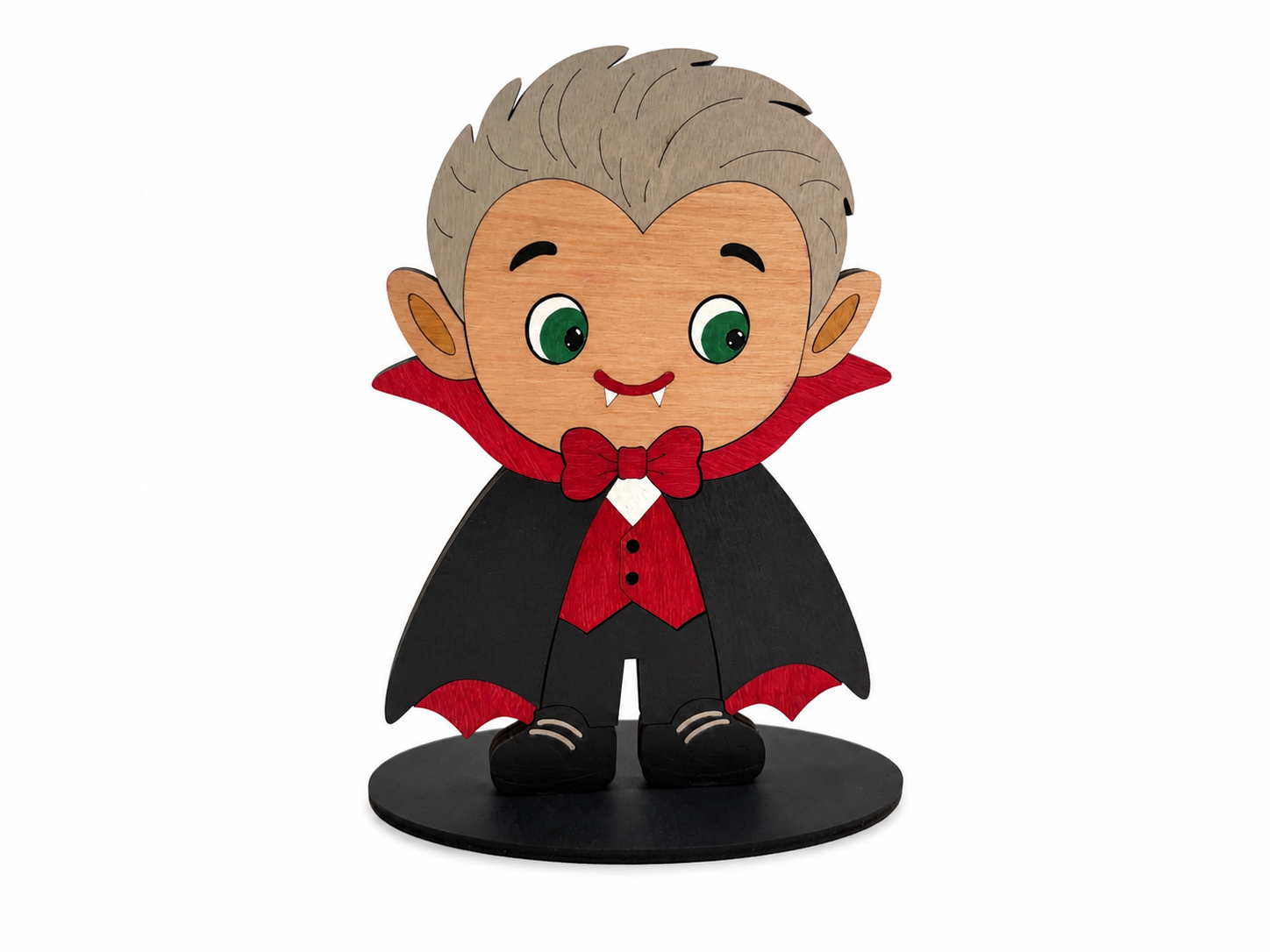 A cartoon-style vampire figurine with gray hair, green eyes, and fangs, wearing a black cape with red lining and a red bow tie, standing on a black circular base against a white background.