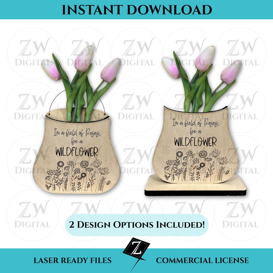 Digital listing image displaying two wooden laser-cut vases with engraved “In a field of roses, be a wildflower” messages and flower doodles, each holding real pink tulips. One vase design includes a hanging wire; the other rests on a rectangular base. Text reads “Instant Download,” “2 Design Options Included,” and “Laser Ready Files - Commercial License.”