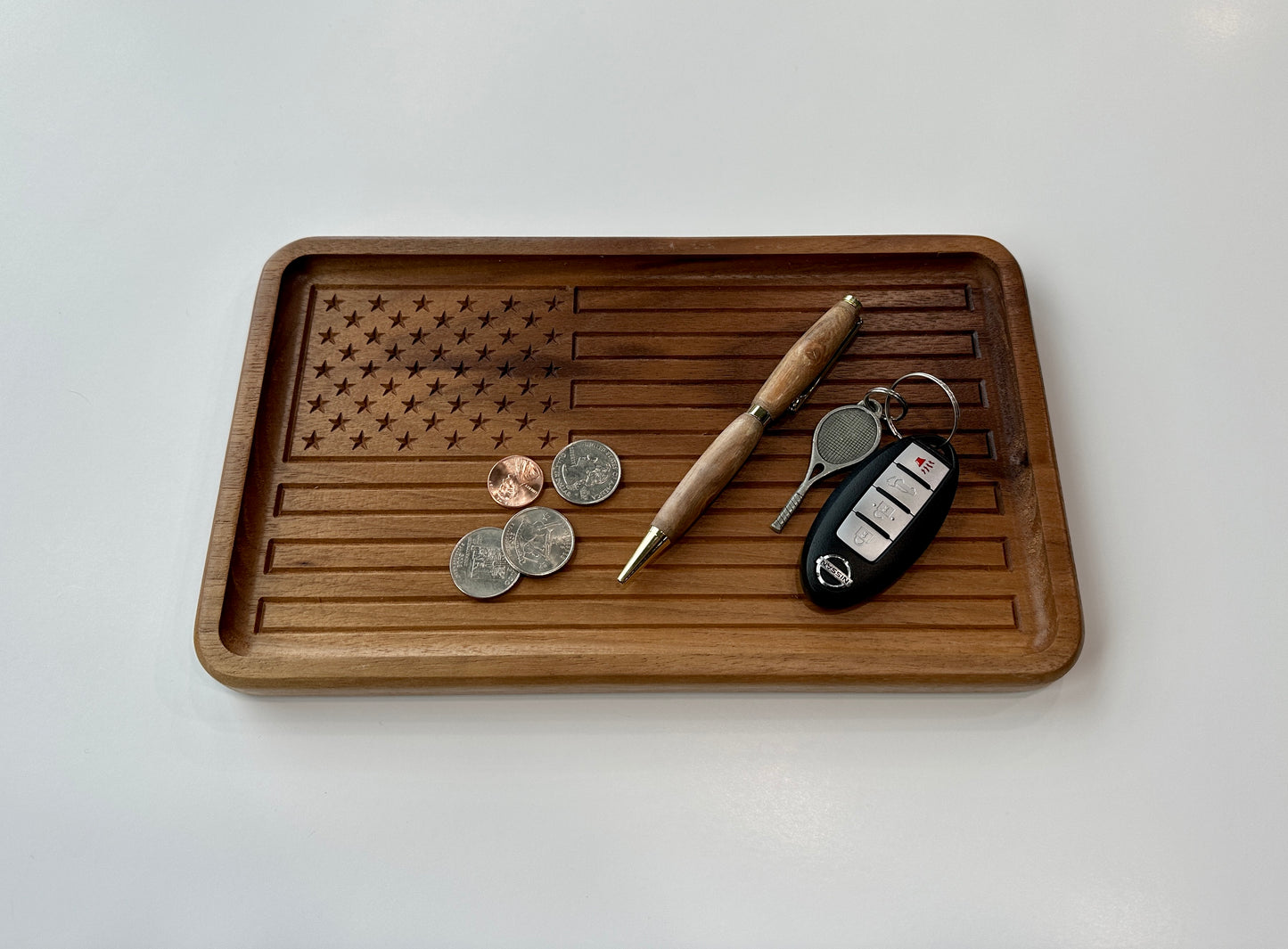 The handmade walnut wood American Flag tray in use. It is holding coins, a pen, and keys.