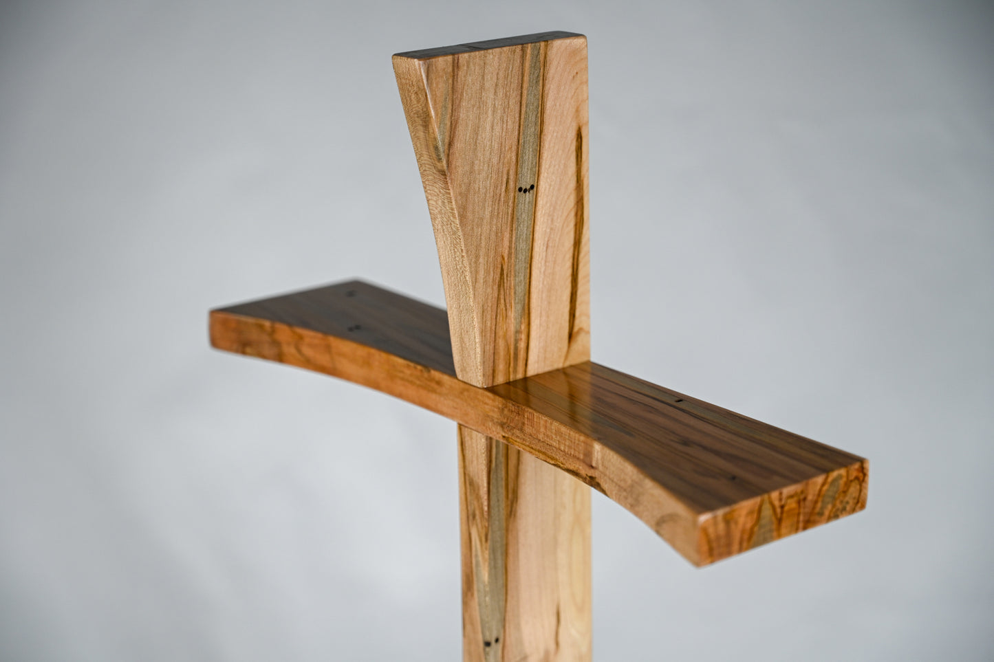 A close up angled view of the Ambrosia Maple Modern Cross. Showing the unique wood grain pattern.