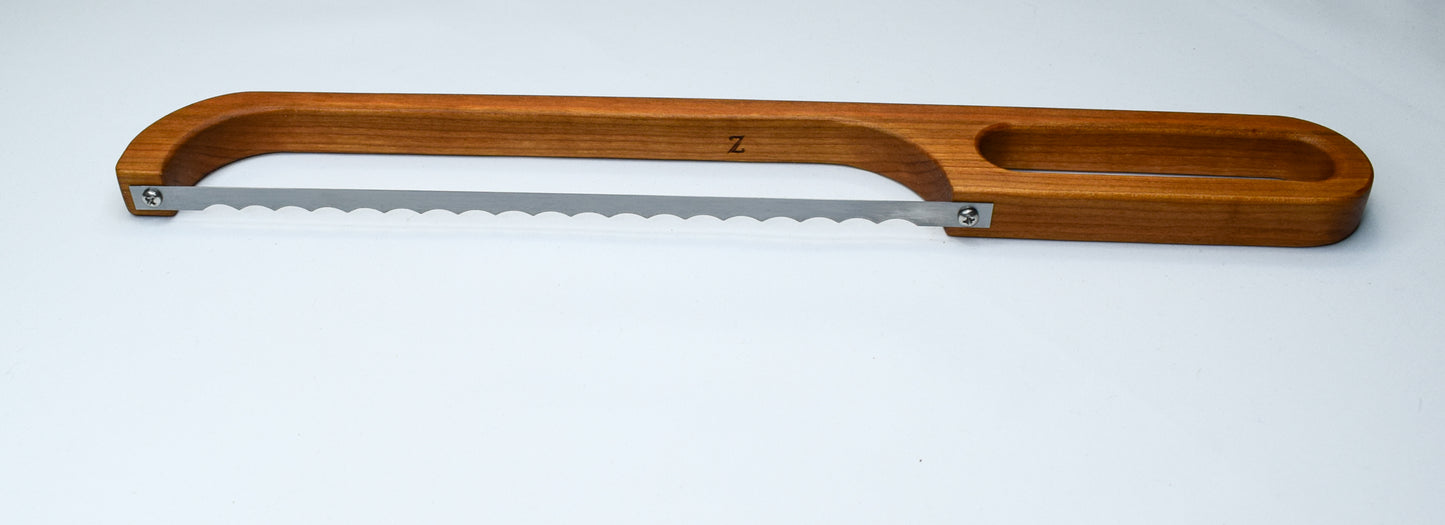 A handmade Cherry Wood bow knife used to cut bread, cheese, fruit and more.