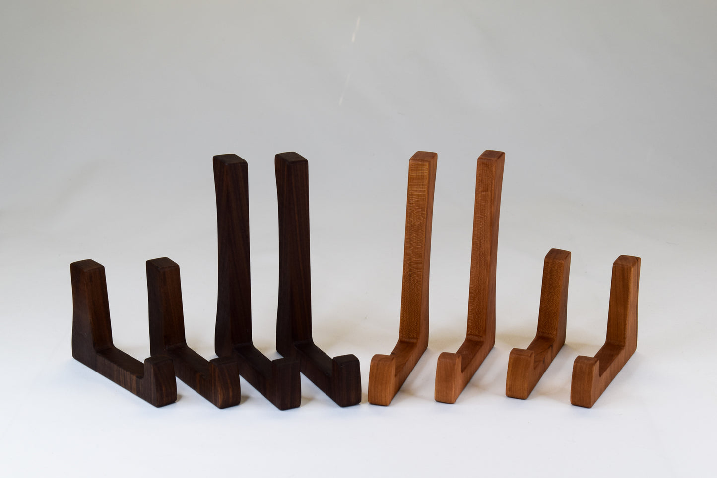 A display of both tall and short cutting board stands made of walnut and cherry wood.