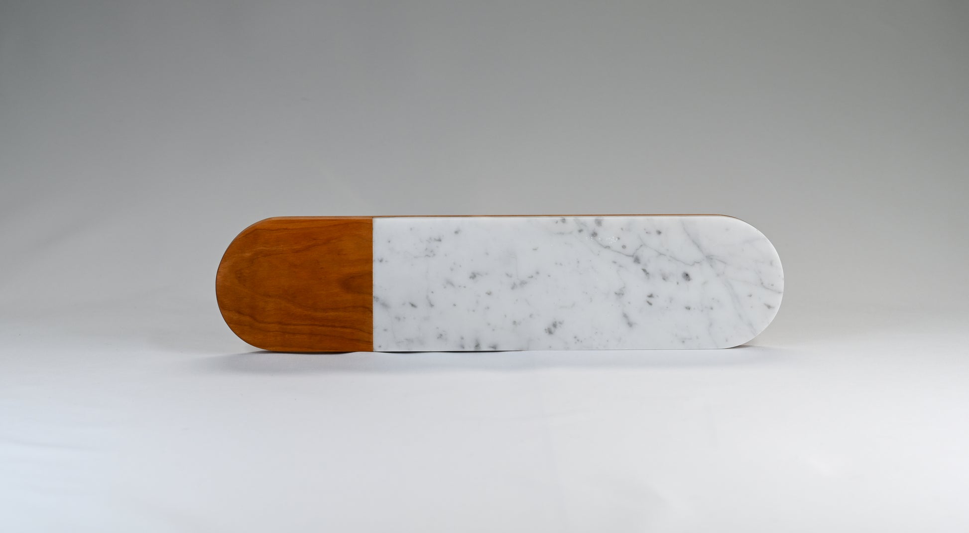 An oval serving board made with domestically sourced cherry wood and Italian marble.