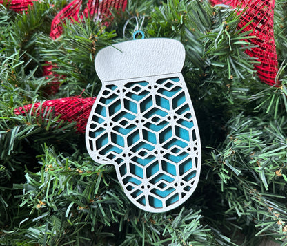 Handmade woodworking gift - A blue, wood mitten ornament with light colored designs on top.