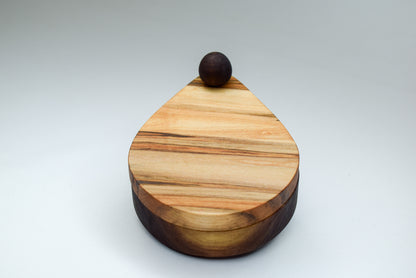 A handcrafted wooden salt cellar showcasing the natural beauty of the wood grain of the maple and walnut woods.