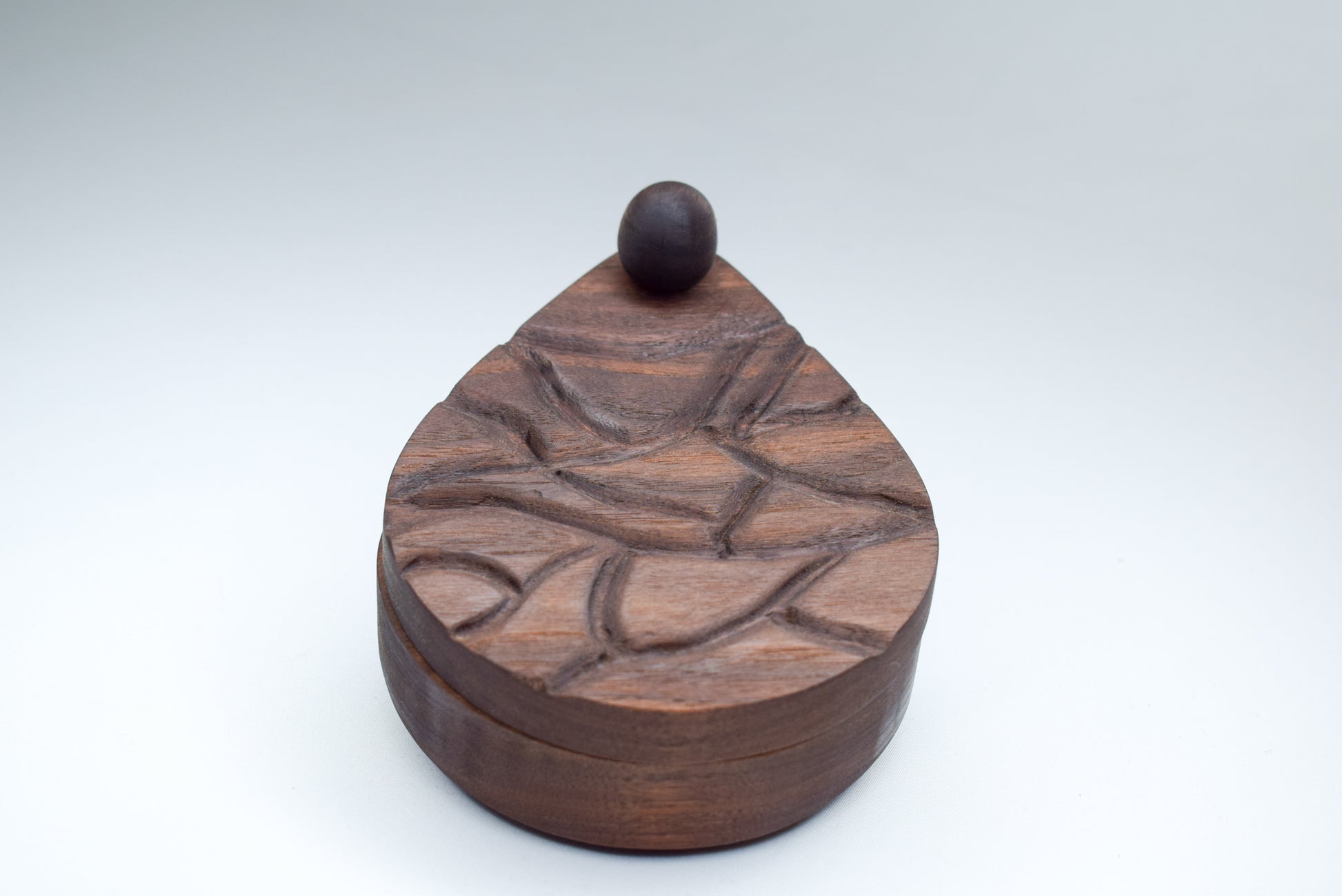 Walnut wood salt cellar with hand-engraved pebble detailing on the top.