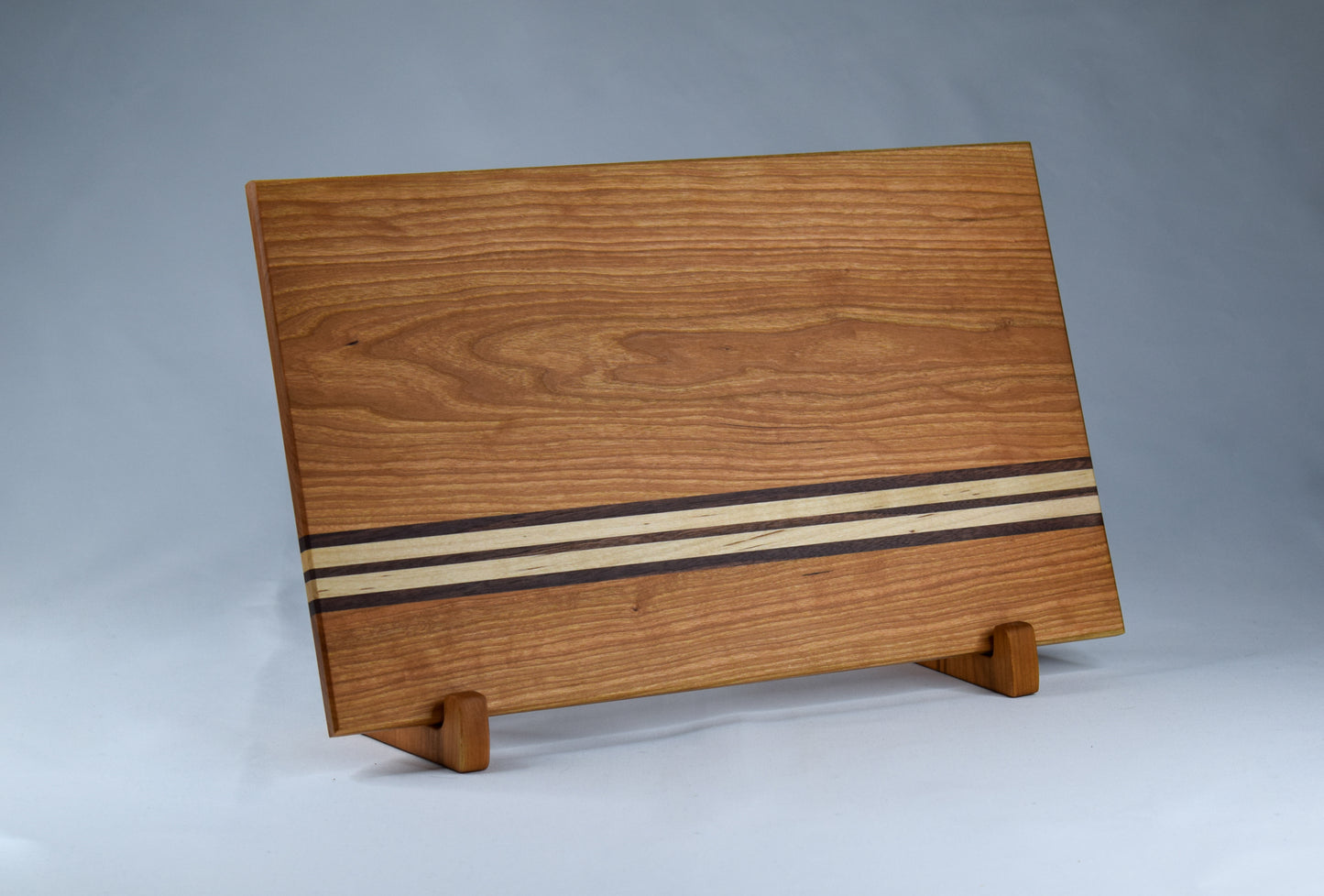 Made of locally sourced cherry, maple, and walnut hardwoods and handmade in our workshop in GA.  This cutting board has a simple stripe design and features non-skid feet.