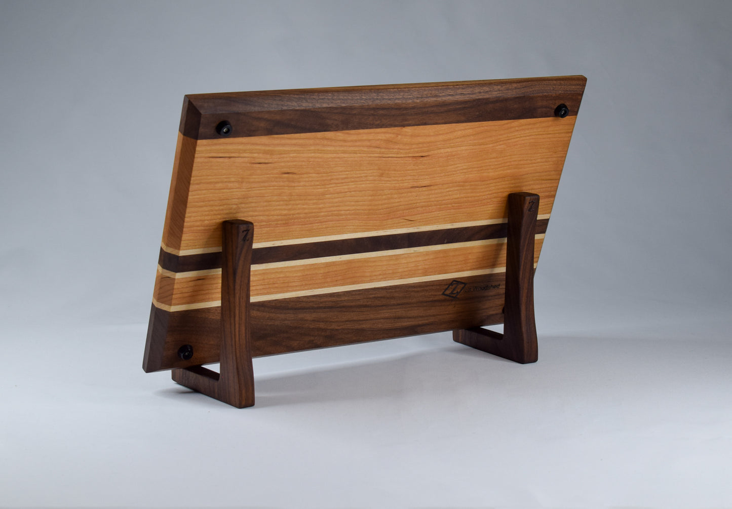 Back view of striped cutting board displayed on wooden stand featuring rubber feet.