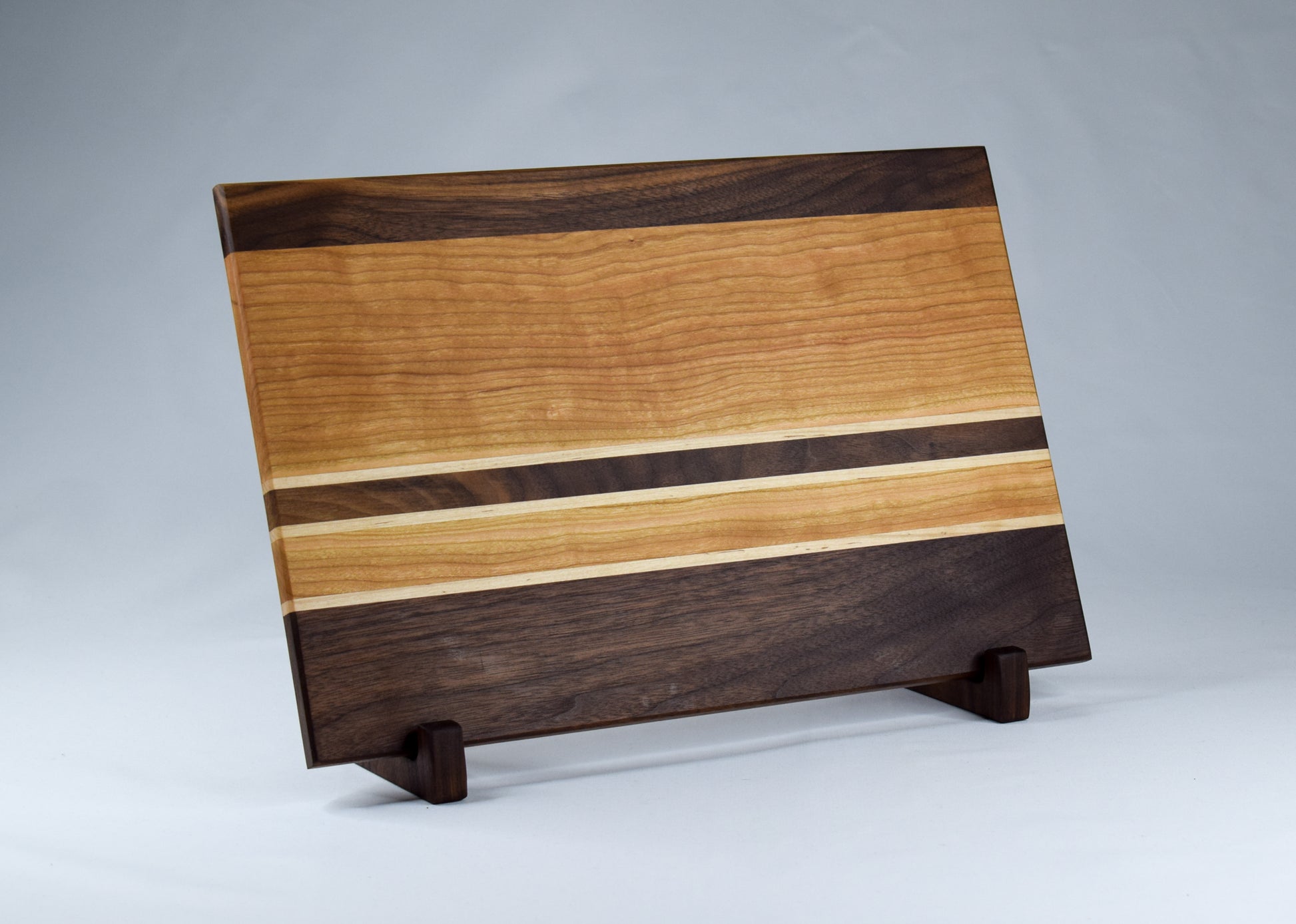 Mutli stripe wooden cutting board handmade with walnut, cherry, and maple cutting board.