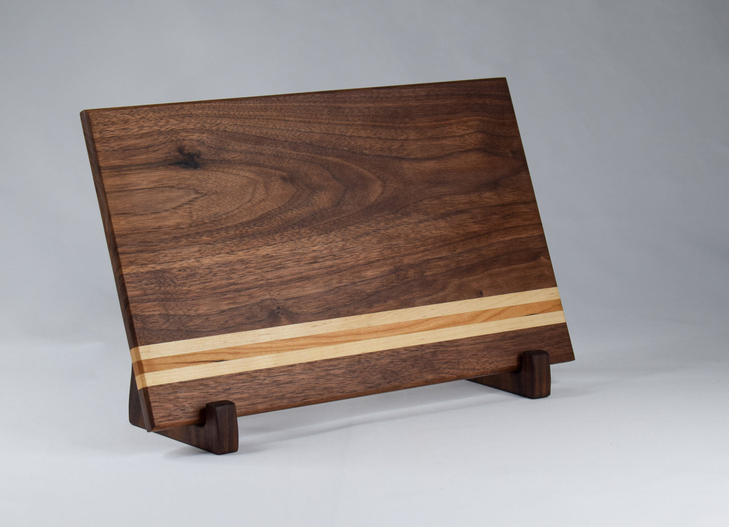 This striped cutting board is the perfect addition to any kitchen with its simple alternating stripes of maple and cherry hardwoods against a walnut backdrop.  Complete with non-skid rubber feet for a sturdy cutting surface, this cutting board will not only provide functionality for the chef in your home, but will also serve as a statement piece in the kitchen.