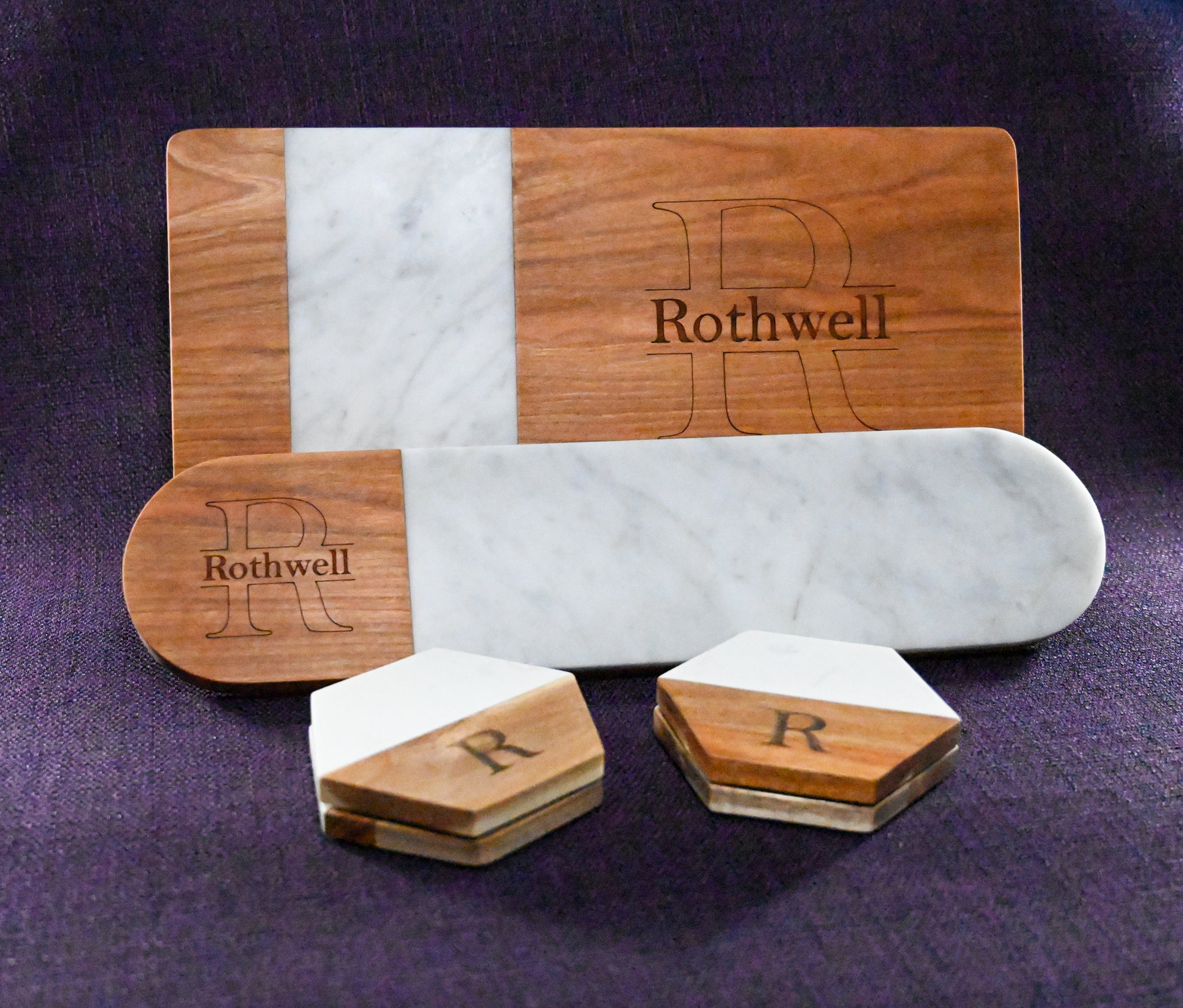 A bundle set of handmade goods made out of Italian marble and domestic hard wood. A rectangle serving board, an oval serving board, and a set of four personalized coasters.