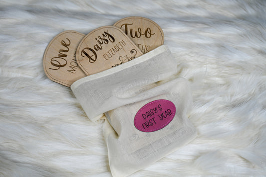 Personalized baby milestones in a muslin bag with a pink laser-engraved patch.