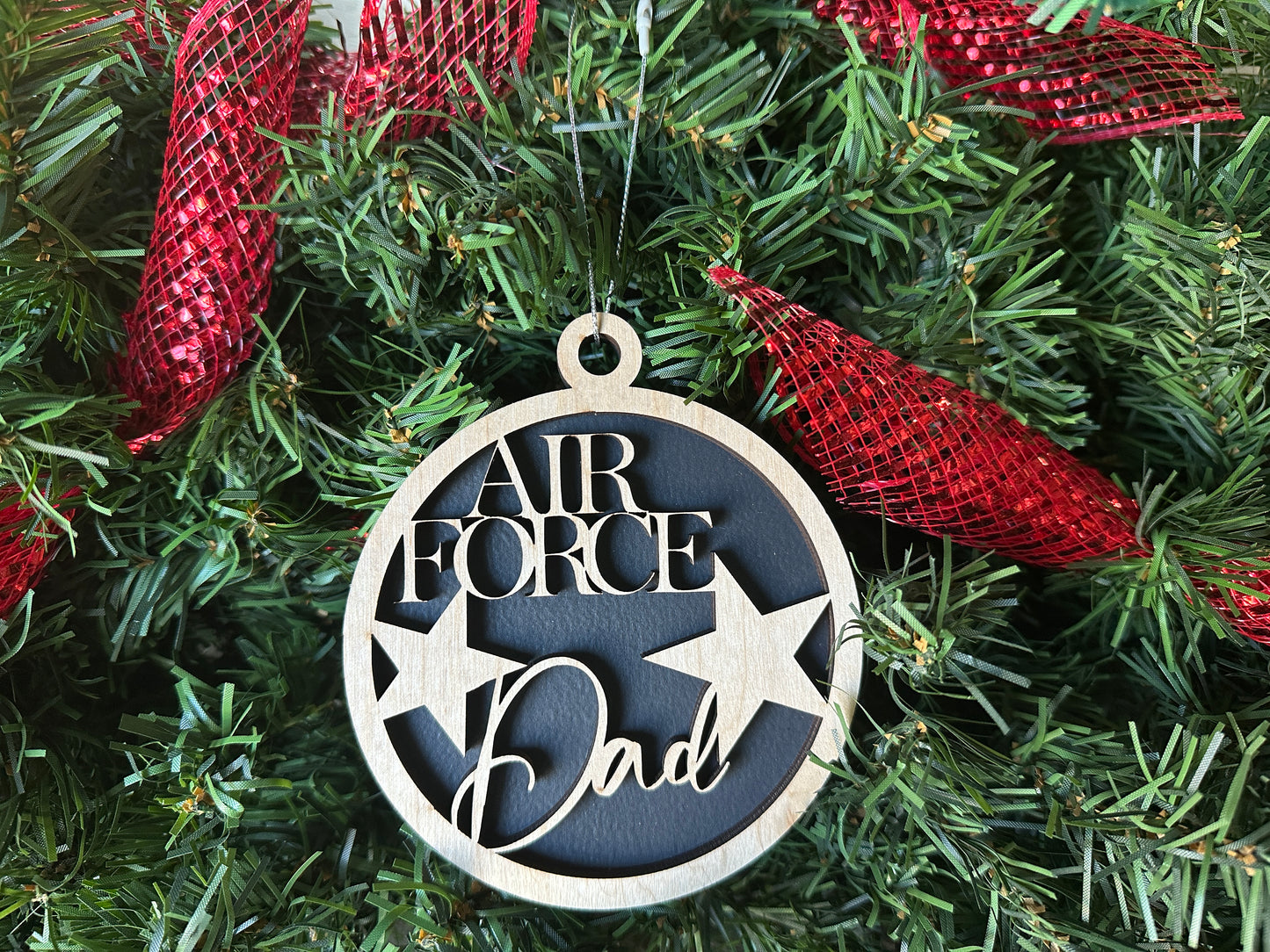 Handmade wood Christmas ornament. Black ornament with light colored birchwood words on top. Words read "Air Force Dad."