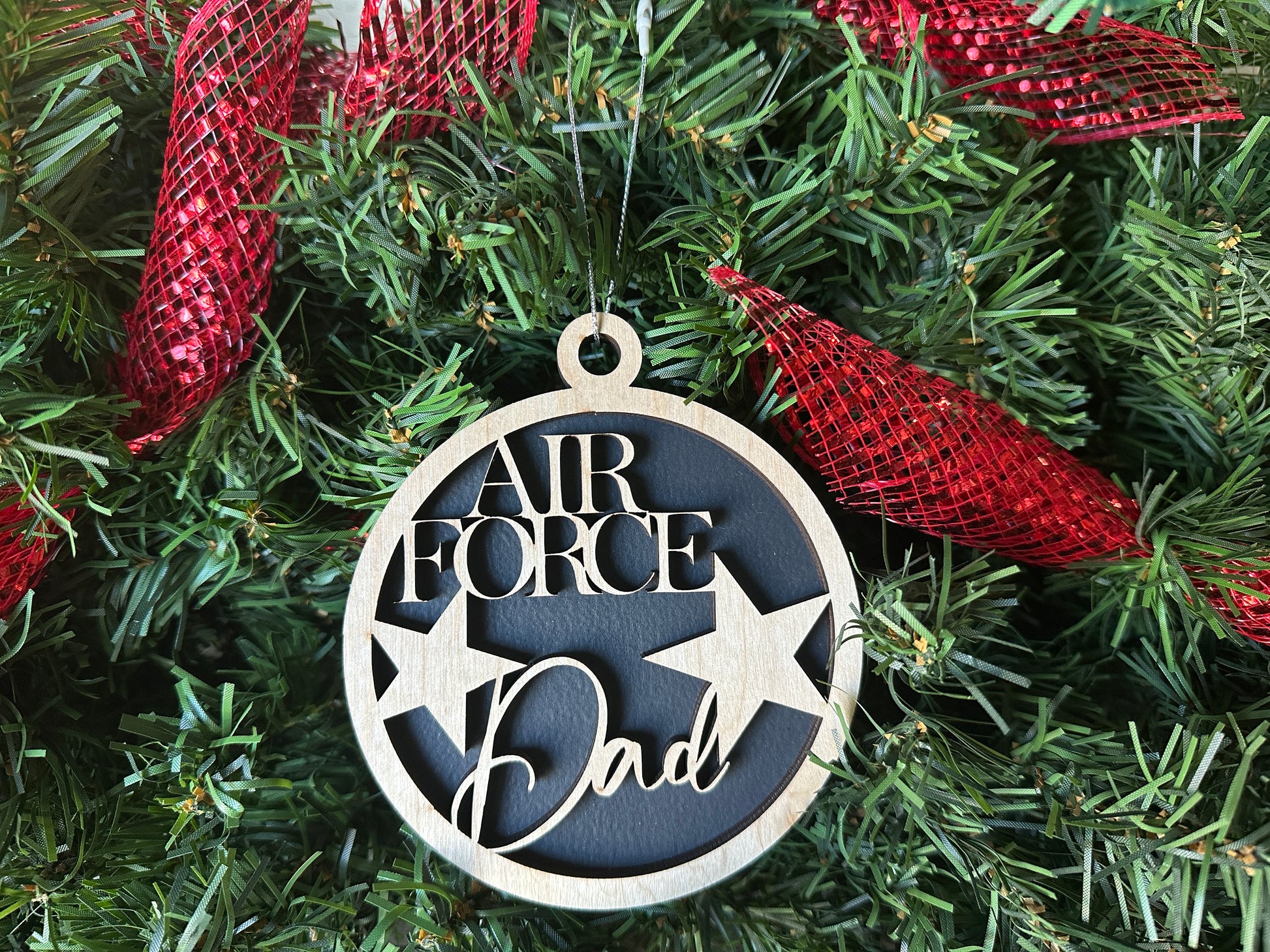 Handmade wood Christmas ornament. Black ornament with light colored birchwood words on top. Words read "Air Force Dad."