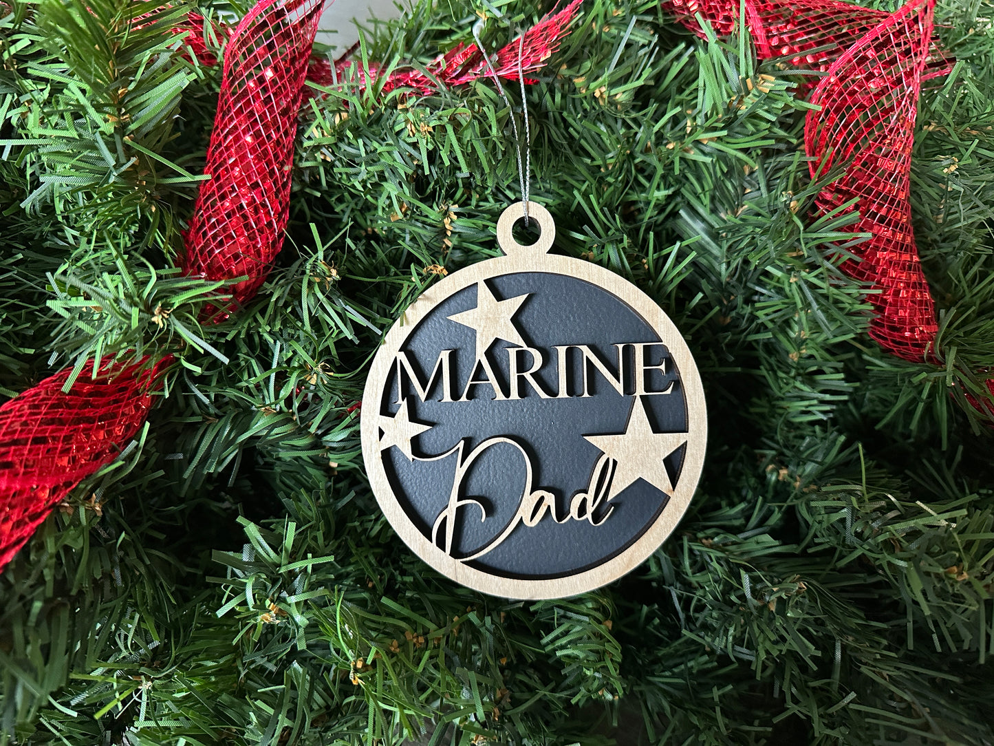 Handmade wood Christmas ornament. Black ornament with light colored birchwood words on top. Words read "Marine Dad."