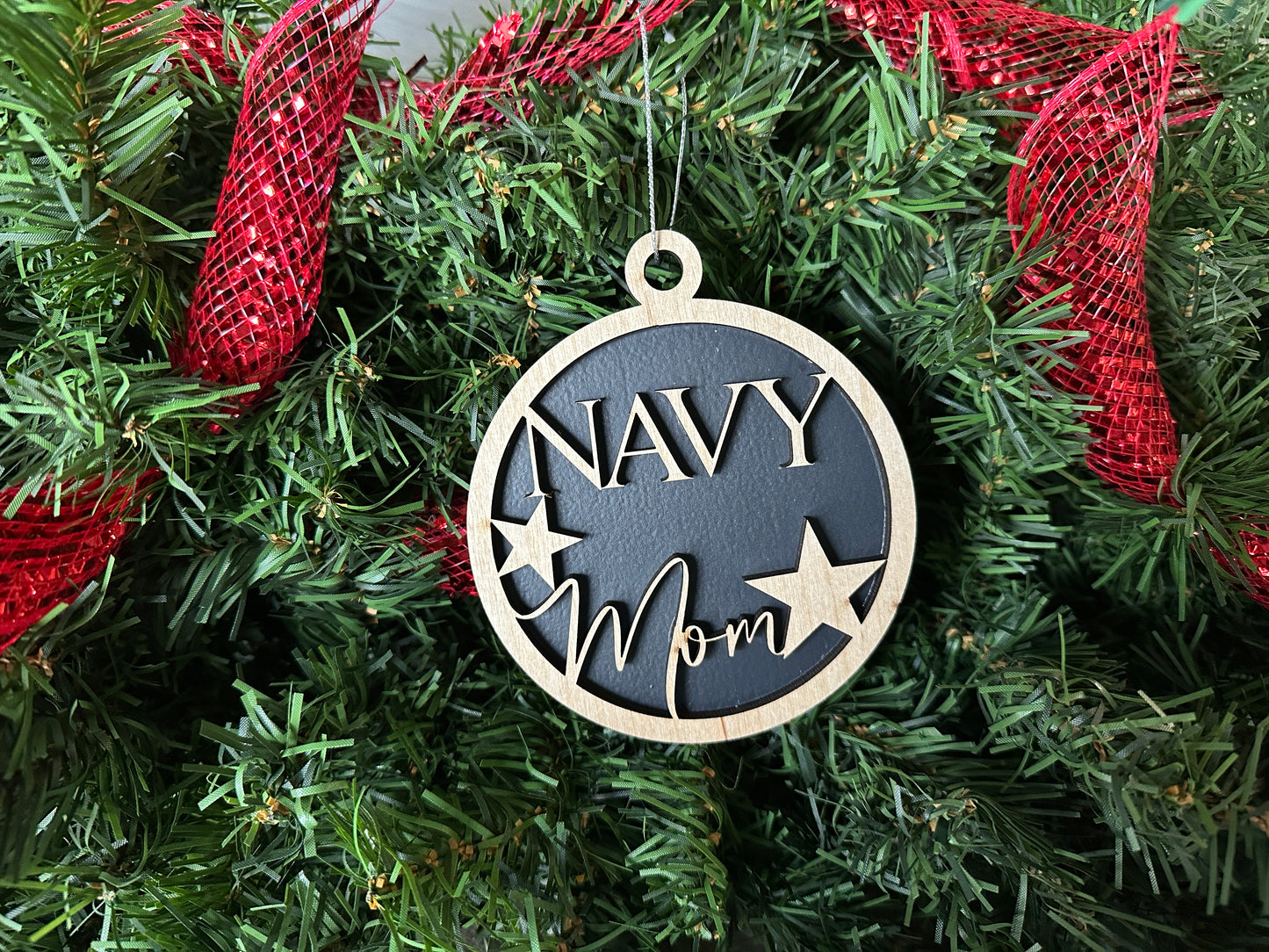 Handmade wood Christmas ornament. Black ornament with light colored birchwood words on top. Words read "Navy Mom."