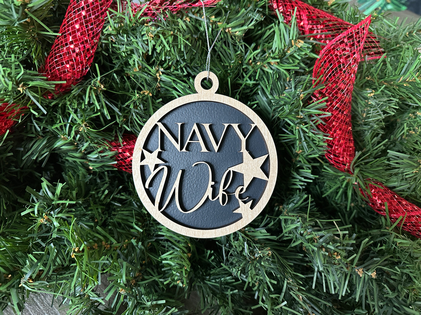 Handmade wood Christmas ornament. Black ornament with light colored birchwood words on top. Words read "Navy Wife."