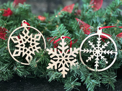 Three unique, laser cut snowflake ornaments displayed on a Christmas tree. Handmade out of birchwood.